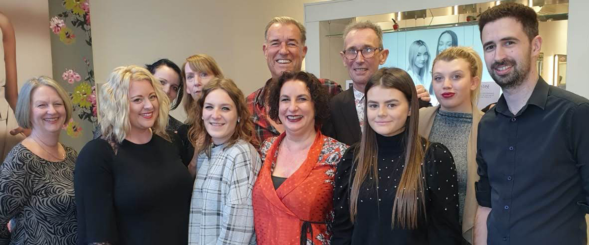 The Saks Addlestone team members, stood up, smiling, and all facing the camera.