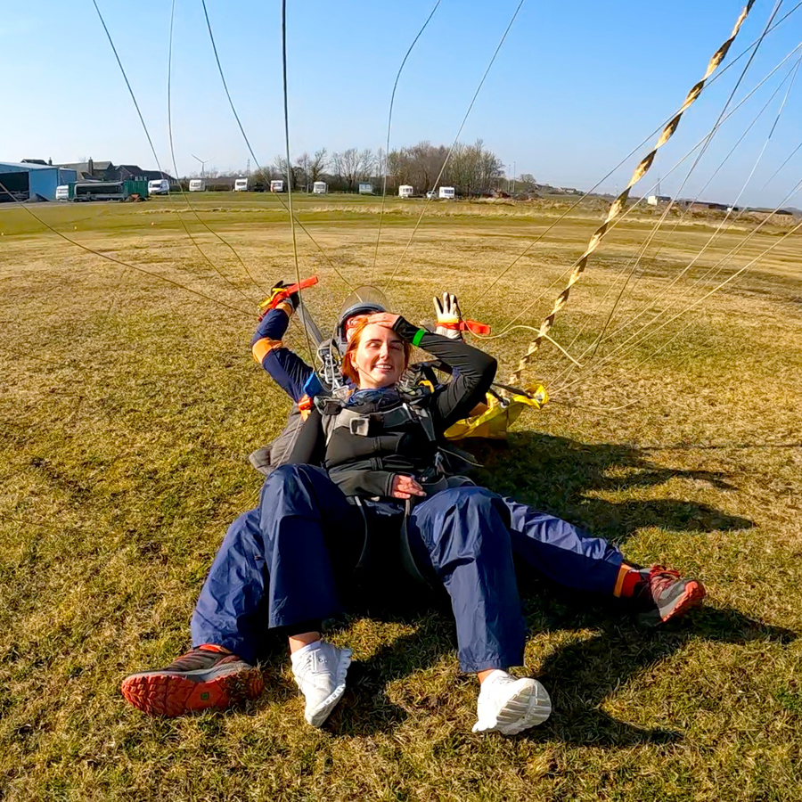 Maddie from Saks Hair in Guisborough having just landed from her skydive challange, laid on the ground with her instructor.
