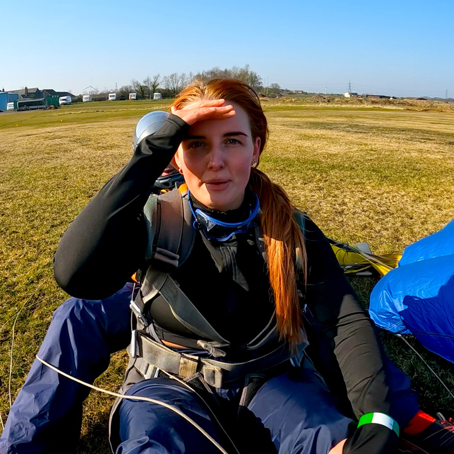 Maddie from Saks Hair in Guisborough having just landed from her skydive challange, having just sat up on the ground with her instructor, looking relieved