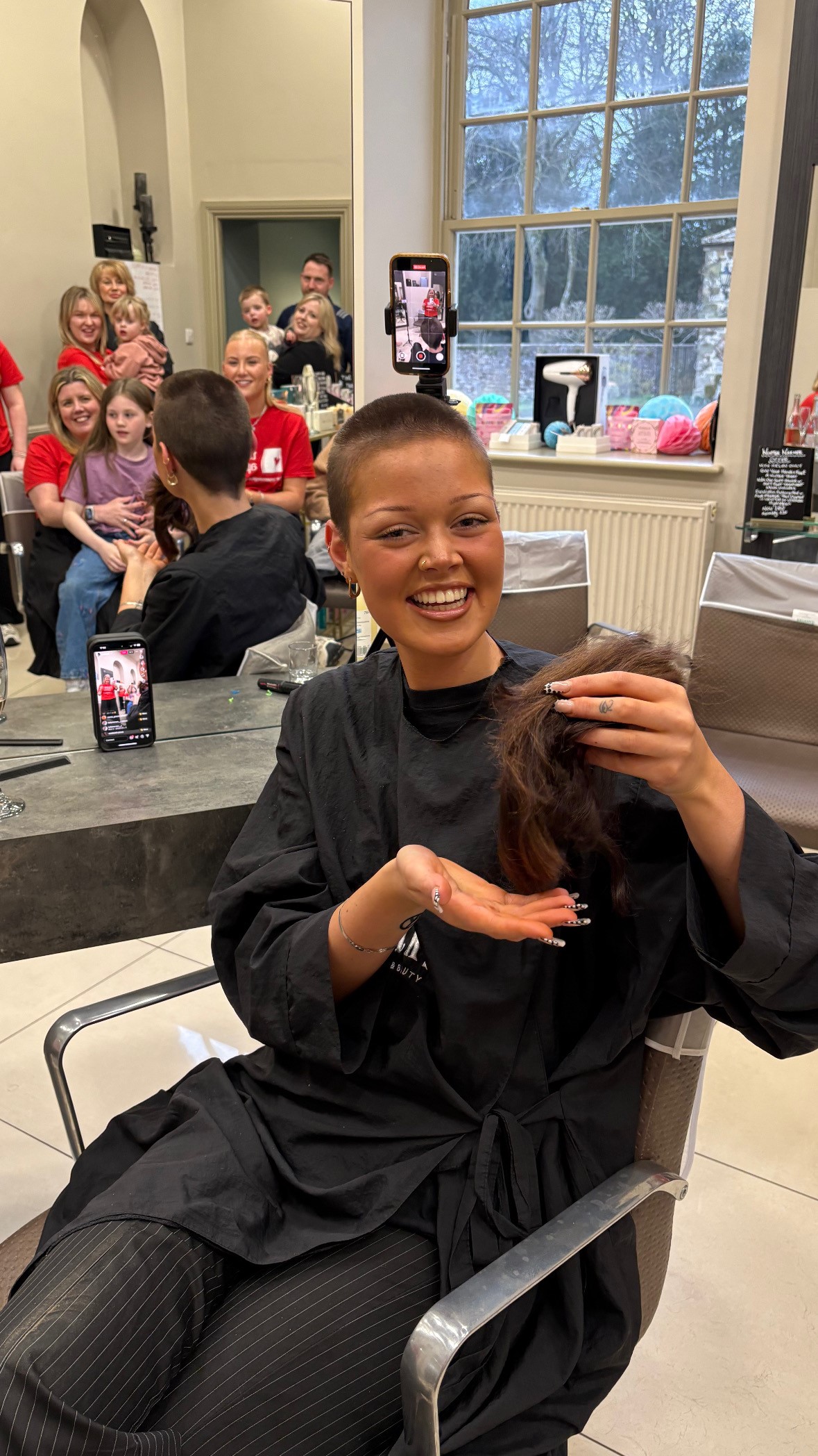 Izzy from Saks Sedbury Hall with her hair in her hand after it as sahved off for charity