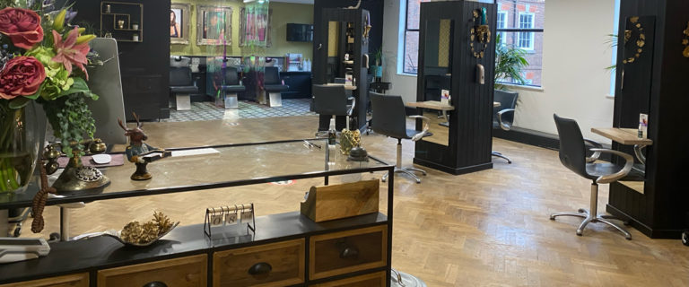 Interior image of Saks Hair salon in York, featuring a glass coffee table, wood flooring and hair styling sections.